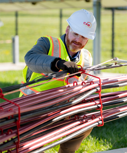 Electrical cables organized in a CAB ModulAir® rack system during an outdoor installation project, with a worker inspecting the cable arrangement.